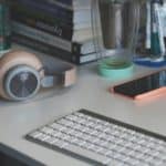grey and white computer keyboard beside grey headphones