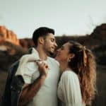 man in black leather jacket kissing woman in white shirt